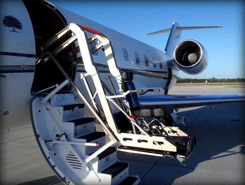 Hydraulic lift raising a passenger in a wheelchair to a private jet door