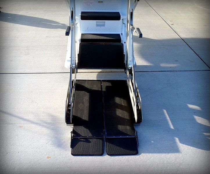 Wheelchair lift ramp lowered to the tarmac beside a private jet in Boca Raton, Florida